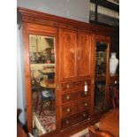 An Edwardian mahogany triple wardrobe with with central drawers flanked by mirror doors on plinth