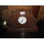 An Art Deco rouge marble mantel clock with fanned ends on plinth base.