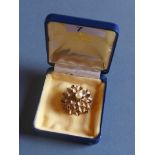 A gold flowerhead form brooch set with rubies and central pearl