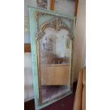 A large Continental wall mirror the arched bevelled plate within gilt and green painted frame