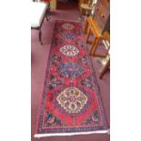 A fine north west Persian Heriz runner 305cm x 85cm repeating stylised medallion on a rouge field