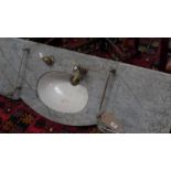 A grey veined marble sink with silvered brass fittings and porcelain basin