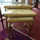 A Regency style brass and onyx nest of three low tables raised on castors