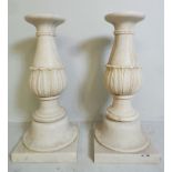 A pair of classical white marble pedestal columns having carved acanthus leaf decoration raised on