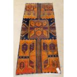 A Persian khotan design rug, the repeated geometric medallions in vibrant orange tones on a noire