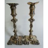 A pair of Victorian silver candlesticks with ornate rococo style bases, weighted with leather base