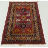 An antique Caucassian rug, the central kazak design on a ruby border within multiple corresponding