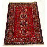 An antique Caucassian rug, the central Lazgy design on a ruby ground, within multiple