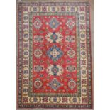 A fine kazak rug, the repeated foliate medallions on an abrashed terracotta ground within multiple