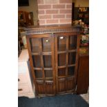 AN OAK LINENFOLD GLAZED BOOKCASE