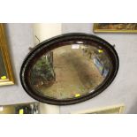 A CARVED OX BLOOD MAHOGANY OVAL SHAPED MIRROR