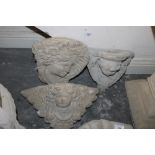 A STONE WALL MOUNTED CHERUB'S FACE PLANTER WITH TWO STONE WALL MOUNTED PLAQUES OF A LADY'S FACE +