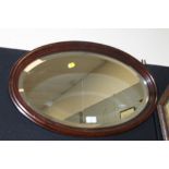 AN OAK FRAMED OVULAR BEVEL EDGE WALL MIRROR