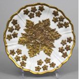 Biedermeier-Prunkteller, Meissen. Fahne mit Blüten und Spiegel mit Weinblättern im Relief, vergoldet
