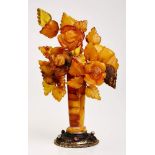Bernsteinstrauß, um 1890.Plast. Blumen u. Blätter aus geschnitztem Bernstein, m. Draht an Vase
