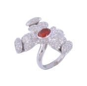 A fire opal and diamond dress ring,   designed as a flower head, the central oval shaped fire opal