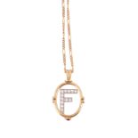 A diamond set pendant on chain,   the diamond set 'F' within an oval surround with a circular