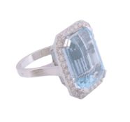An aquamarine and diamond ring,   the rectangular shaped aquamarine in a four claw setting within a