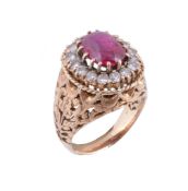 A ruby and diamond cluster dress ring,   the oval cabochon ruby within a surround of brilliant cut