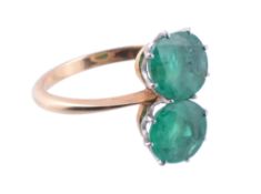 A two stone emerald ring  , the circular shaped emeralds within claw settings, finger size N