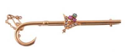 A gem set bar brooch,   circa 1900, the crook shaped bar with an applied foliate panel set with