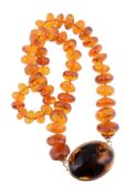 A graduated amber bead necklace,   composed of disc shaped amber beads, on a knotted string, to the