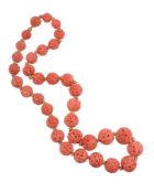 A carved coral bead necklace,   the graduated circular beads carved with Oriental designs, with