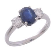 A sapphire and diamond ring,   the central oval shaped sapphire in a claw setting, between two