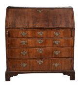 A George II walnut bureau  , circa 1740, the fall opening to an arrangement of pigeon holes and
