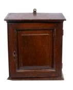 A spice cupboard,   first half 18th century, the panel door enclosing an arrangement of drawers,