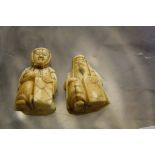 Two similar Japanese ivory netsuke's, of men seated with panels  , 3.5cm and 4cm high (2)