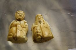 Two similar Japanese ivory netsuke's, of men seated with panels  , 3.5cm and 4cm high (2)