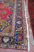 A Persian style carpet   with a central medallion and floral motif on a red ground.340cm x 245cm