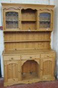 A pine dresser   with leaded glazed cabinets to the upper section with drawers and cupboards to the