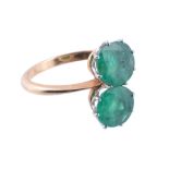 A two stone emerald ring  , the circular shaped emeralds within claw settings, finger size N