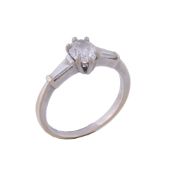 A diamond three stone ring,   the central oval shaped diamond claw set between tapered baguette cut