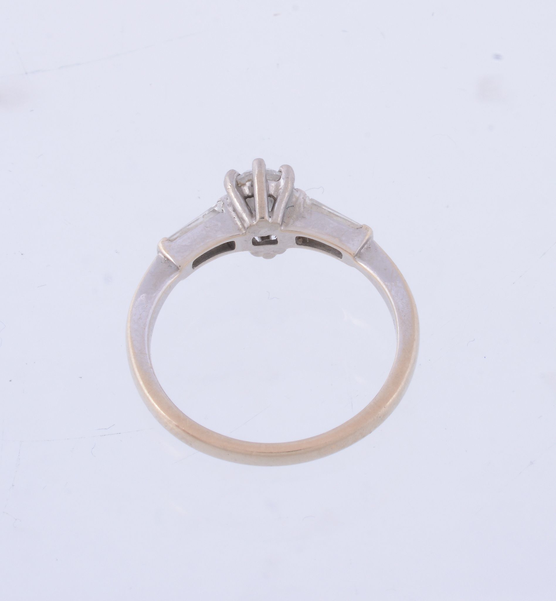 A diamond three stone ring,   the central oval shaped diamond claw set between tapered baguette cut - Image 2 of 3