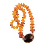 A graduated amber bead necklace,   composed of disc shaped amber beads, on a knotted string, to the