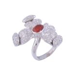 A fire opal and diamond dress ring,   designed as a flower head, the central oval shaped fire opal