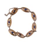 A gold and sapphire bracelet, circa 1910, composed of oval shaped links each...   A gold and