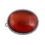 An amber and half pearl brooch, the oval cabochon amber within a border of...   An amber and half
