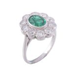 An emerald and diamond ring, the central oval cut emerald collet set within...   An emerald and