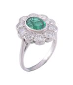 An emerald and diamond ring, the central oval cut emerald collet set within...   An emerald and
