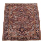 A Heriz carpet, the madder field with central navy medallion decorated with...   A Heriz carpet,