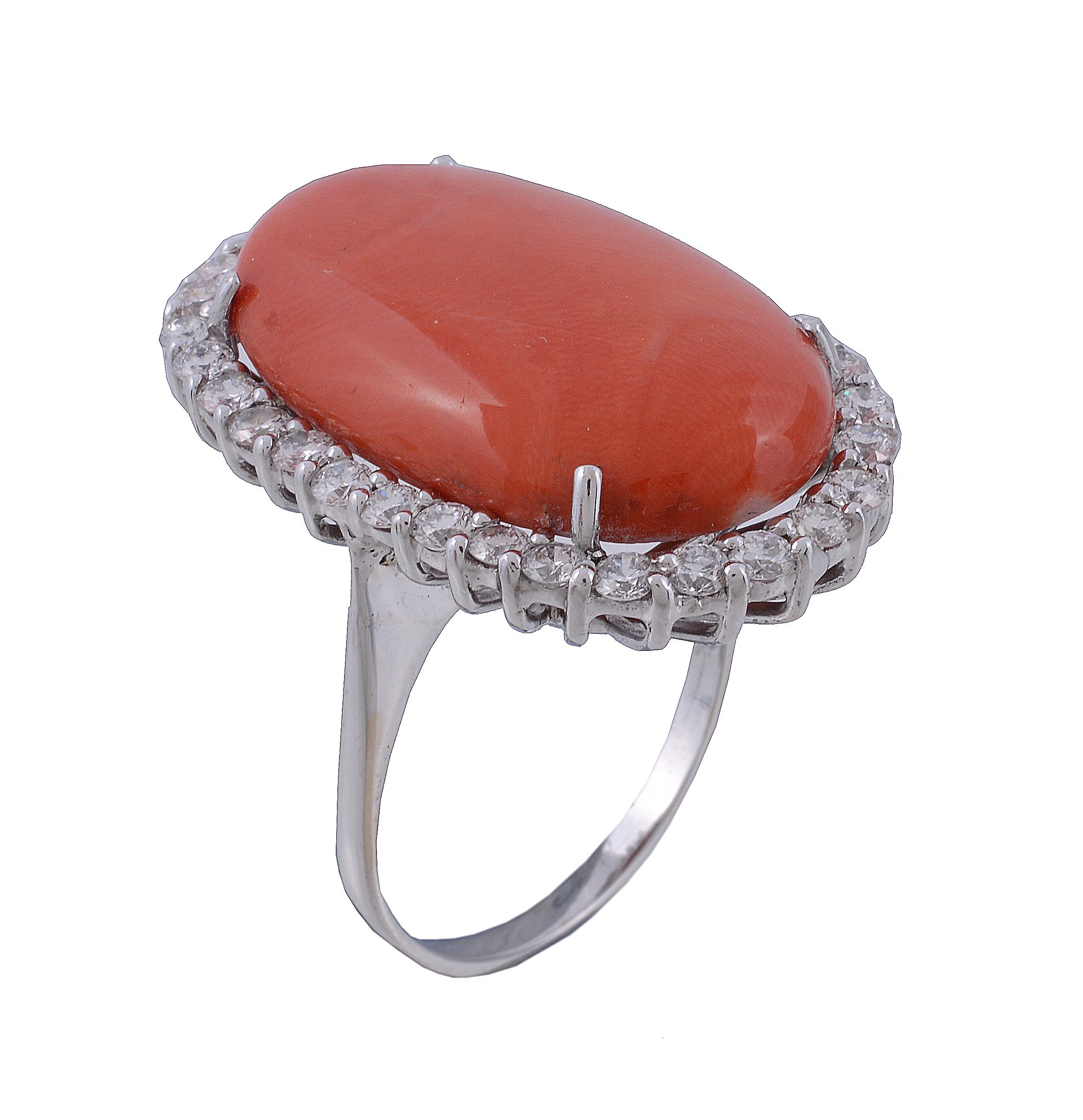 A coral and diamond ring, the oval cabochon coral claw set within a surround... A coral and