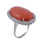 A coral and diamond ring, the oval cabochon coral claw set within a surround... A coral and