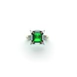 An emerald and diamond ring set with a step-cut emerald