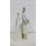 A Lladro porcelain female figure, modelled standing with a basket in her arms together with