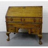 An oak bureau with brass mounts the fall front opening to reveal a fitted interior over two short