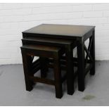 A contemporary stained hardwood nest of three tables with cross side supports, tallest 50cm x 60cm